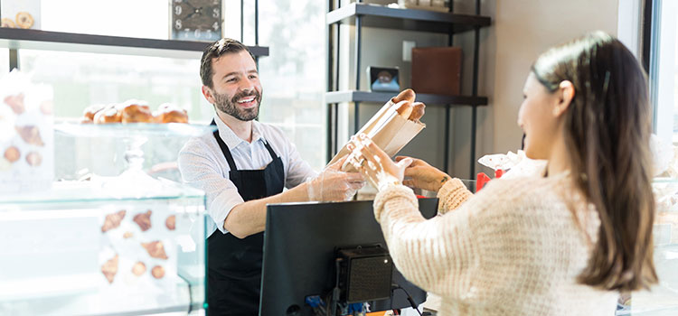 male baker selling baguettes to woman customer